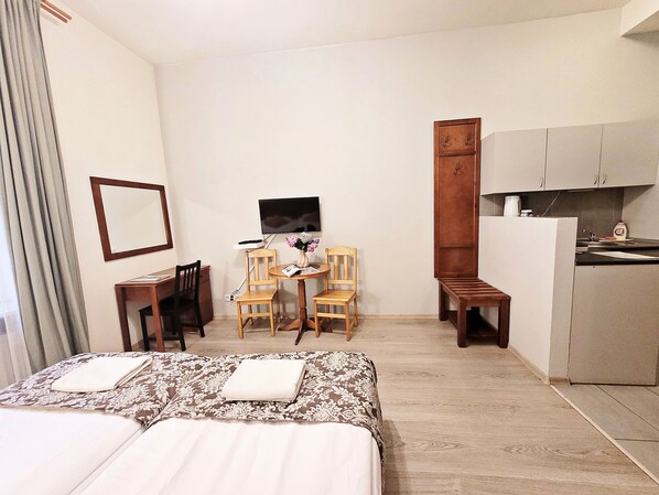 A hotel room with a bed, a desk with a chair, a small table with a chair, a television, and a kitchenette. - DReAM Post Aparthotel (Kraków)