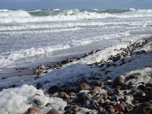 A rocky shoreline with waves crashing onto the beach. - 10 Person Holiday Home in Graested (Graested)