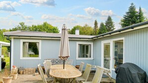 A wooden deck with a round table and chairs, a barbecue grill, and a covered umbrella. - 10 Person Holiday Home in Graested (Graested)
