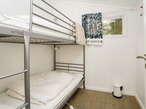 A bunk bed room with a window, a small trash bin, and a curtain. - 10 Person Holiday Home in Graested (Graested)