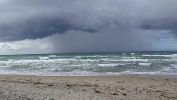En strand med bølger og en overskyet himmel.