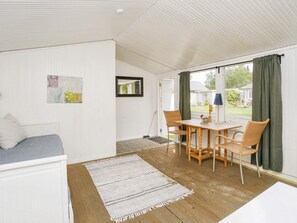 A room with a sofa, a dining table with chairs, a rug, a mirror, and a view of the outdoors. - 10 Person Holiday Home in Graested (Graested)