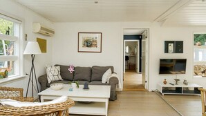 A living room with a sofa, a coffee table, a lamp, and a television. - 10 Person Holiday Home in Graested (Graested)