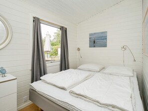 A bedroom with a bed, a bedside table, a window with curtains, a wall-mounted lamp, and a painting. - 10 Person Holiday Home in Graested (Graested)