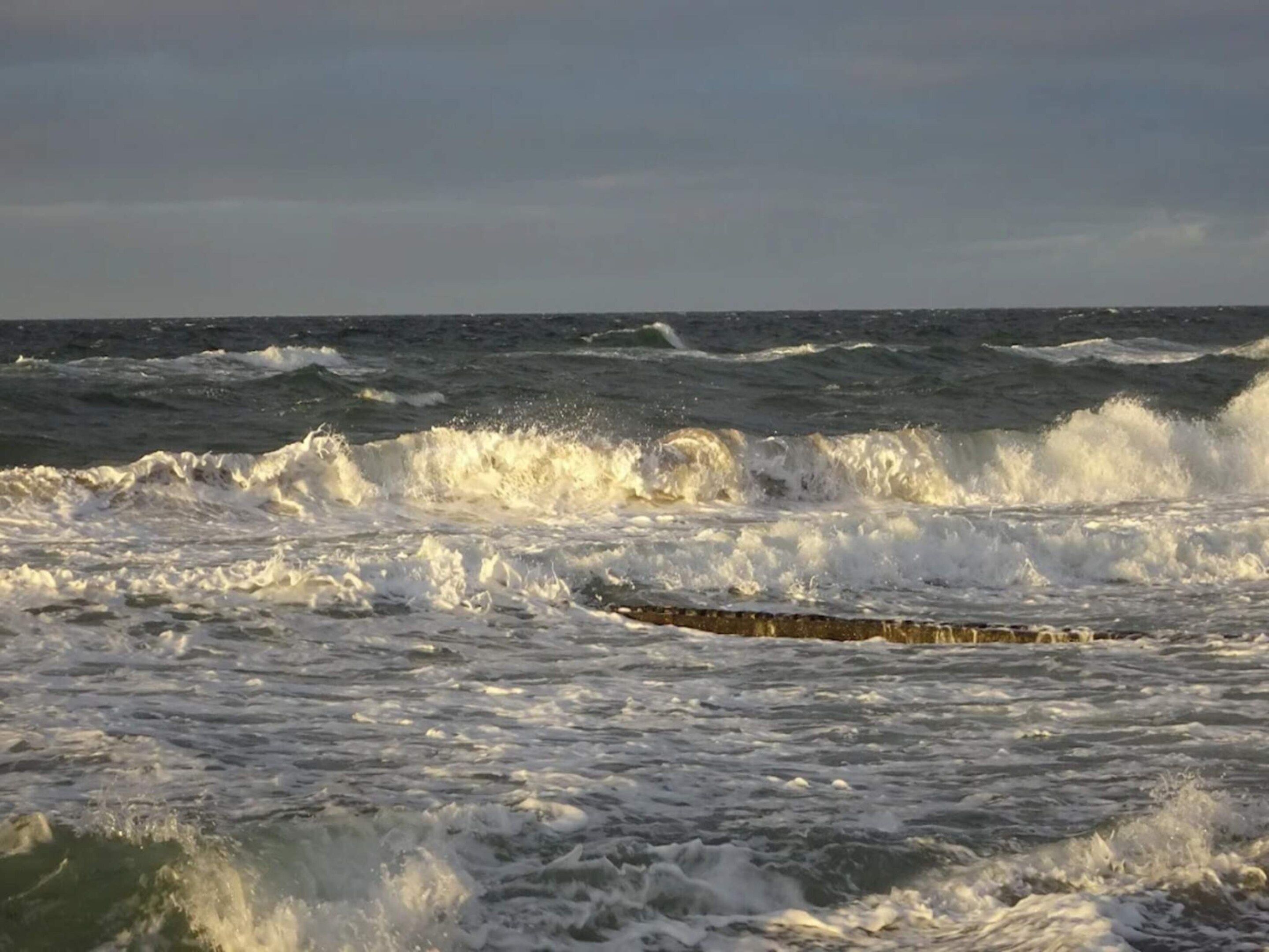 Une mer agitée, avec des vagues qui s’écrasent sur une côte rocheuse.