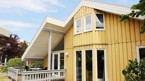 A yellow wooden house with a covered porch and large windows. - Ferienhaus im Skandinavischen Stil (Mirow)