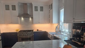 A modern kitchen with white cabinets, a stainless steel stove, and a marble island. - NEW! Gorgeous 4-bedroom in quiet,  upscale  neighborhood near White Rock Lake, (Dallas)