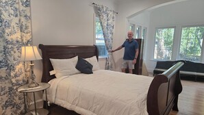 A neatly made bed with a wooden headboard, a bedside lamp, and a floral-patterned curtain. - NEW! Gorgeous 4-bedroom in quiet,  upscale  neighborhood near White Rock Lake, (Dallas)