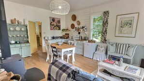 Une cuisine chaleureuse avec un coin repas, un canapé et une table en osier sur laquelle sont posés des magazines.