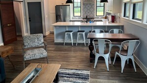 Una cocina moderna con una isla central, taburetes de bar y una mesa de comedor con sillas.