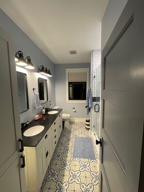 Un baño con dos lavamanos, un inodoro y una zona de ducha.
