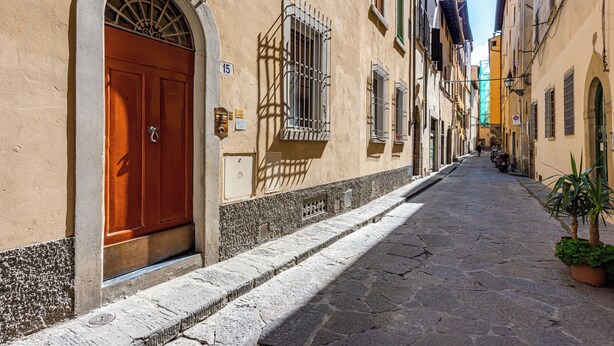 A narrow cobblestone street flanked by historic buildings with arched doorways and barred windows. - Passera Royal Suite - Your luxury cozy nest in the very heart of Renaissance (Firenze)
