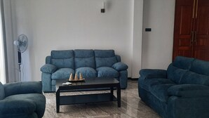 A living room with a blue sofa set, a coffee table, and a wooden door. - Elegant family friendly villa close to airport & beach (Pamunugama)