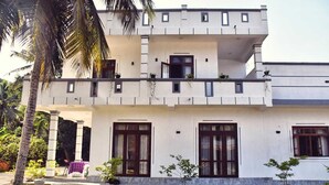 A two-story building with a flat roof, white exterior walls, and a balcony on the upper floor. - Elegant family friendly villa close to airport & beach (Pamunugama)