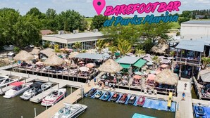 A marina with multiple boats docked, a bar area with umbrellas, and a building with a flat roof.
