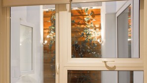 Una habitación con piso de madera, una puerta blanca y una ventana que da a una pared de madera y una planta.