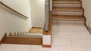 Una escalera de madera con barandillas, que lleva a una plataforma con una lámpara.