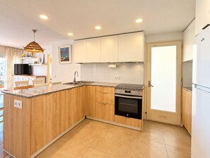 A modern kitchen with wooden cabinets, a built-in oven, and a sink.
