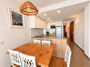 A modern kitchen with a central island, white cabinetry, and a dining area with a wooden table and chairs.