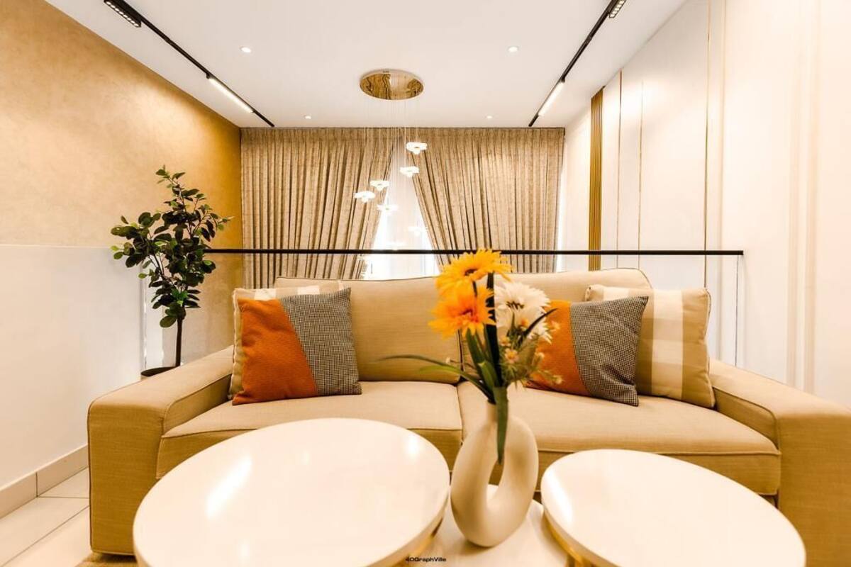 Ett modernt vardagsrum med en beige soffa, två runda bord och en vas med blommor.