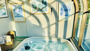 A hot tub with a control panel, surrounded by framed pictures on the wall.