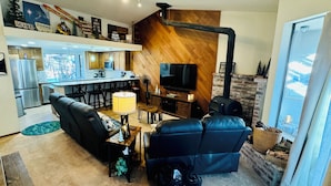 A modern living room with a black leather sofa, a TV, and a fireplace.
