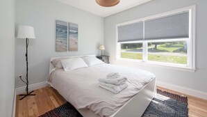 Ein Schlafzimmer mit Bett, einem Fenster mit Jalousien, einer Lampe und einem Bild an der Wand.
