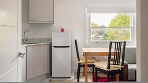 Una cocina compacta con refrigerador, pileta y ventana con vista a árboles.