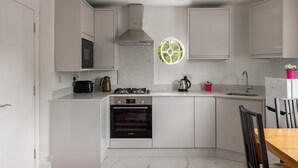 Una cocina moderna con armarios blancos, horno empotrado, microondas y estufa a gas.