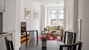 A modern living room with a dining area, featuring a sofa, chairs, a coffee table, and a red rug. - Picktheplace Kensington Lux Apartments (London)