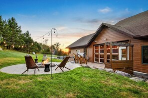 A wooden cabin with a patio area featuring outdoor seating and a fire pit.