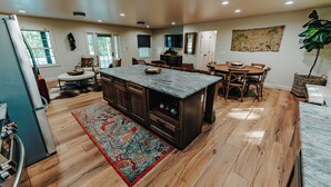 Una cocina amplia con una isla grande, armarios de madera y un comedor con mesa y sillas.