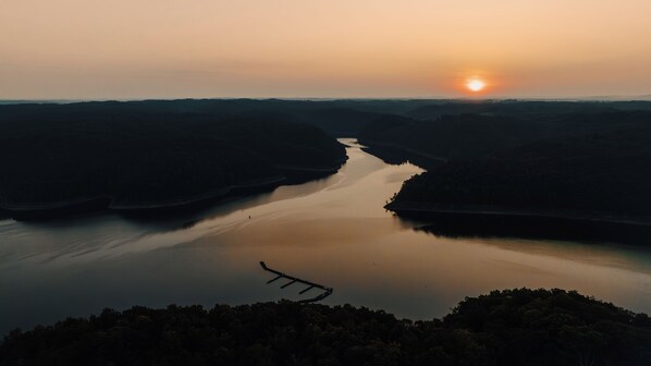 A river with a bridge in the foreground and a sunset in the background.