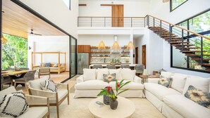 Un vaste espace de vie doté d’un haut plafond, d’un escalier et d’un coin repas aménagé avec des meubles modernes.