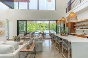 Una cocina moderna con una isla grande, comedor con sillas y vistas al exterior.