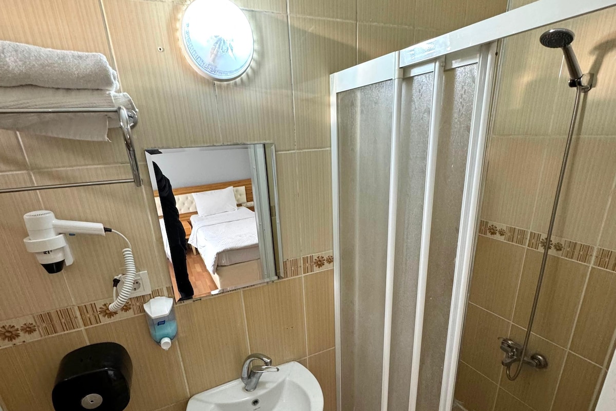 A bathroom with a sink, mirror, towel rack, and a shower enclosure.