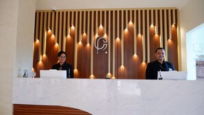 A reception desk with a wooden panel background and a marble counter. - Point C Hotel (Bandung)