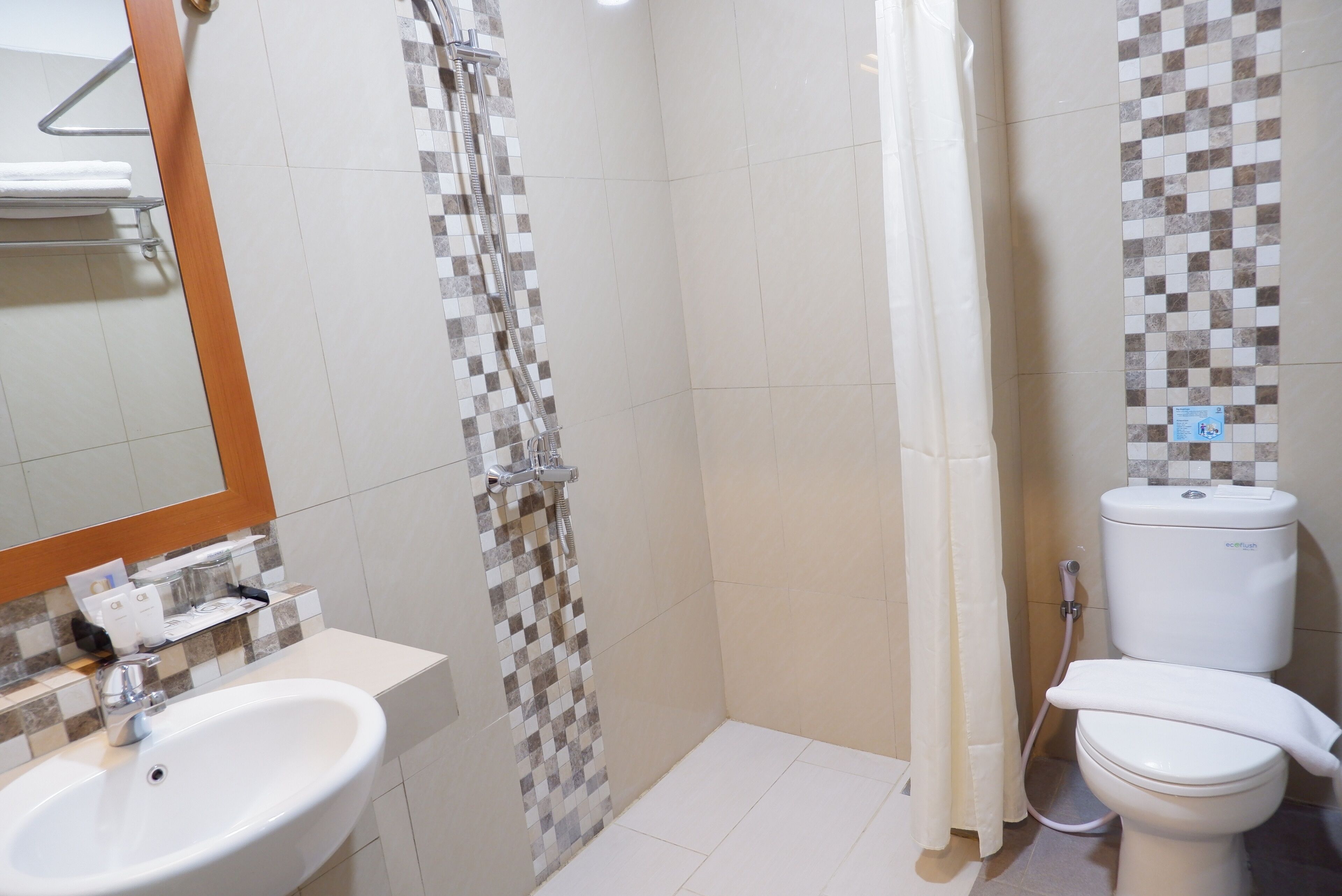 A bathroom with a sink, toilet, shower, and a tiled wall with a checkered pattern.