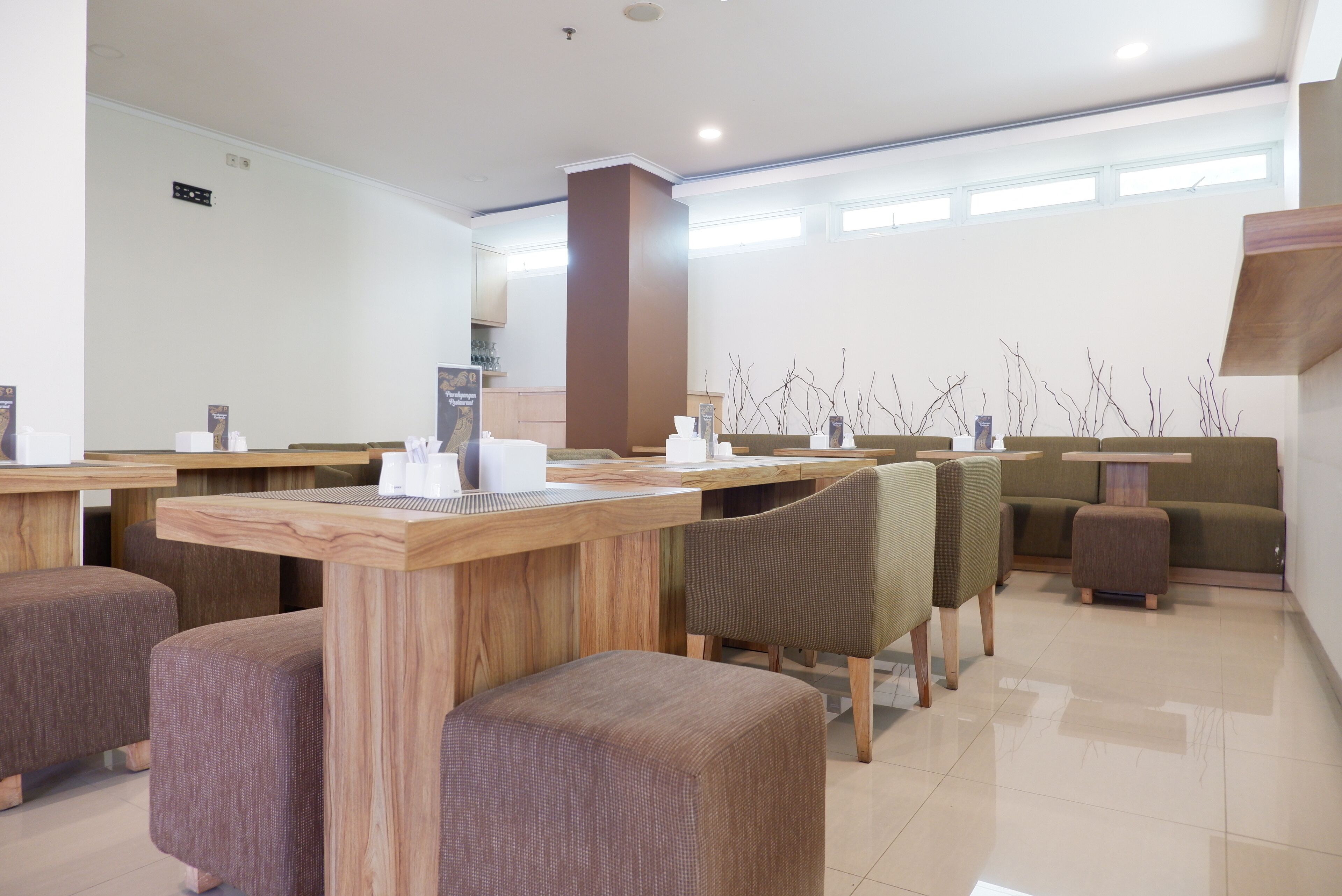 A modern hotel lobby with wooden tables, cushioned seating, and a green sofa.