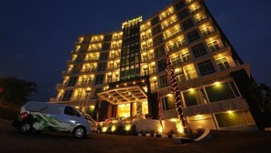 A multi-story hotel with a curved facade, illuminated windows, and a central entrance with a canopy. - Point C Hotel (Bandung)