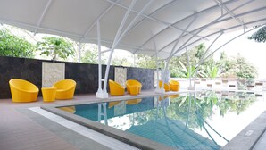 A pool area with yellow chairs and a covered seating area. - Point C Hotel (Bandung)