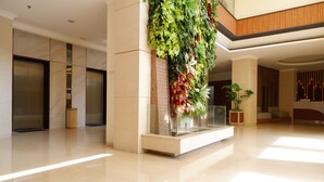 A modern lobby with a polished floor, a vertical garden, and a reception area with a seating arrangement. - Point C Hotel (Bandung)