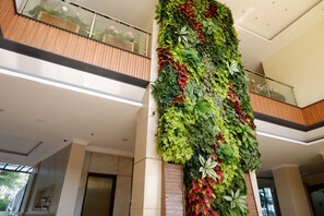 A modern interior with a vertical garden wall, a wooden balcony, and a glass railing. - Point C Hotel (Bandung)