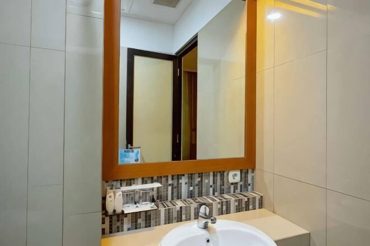 A bathroom with a large mirror, a sink, and a tiled backsplash.