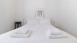 A neatly made bed with white linens and towels, a white headboard, and a wall-mounted artwork of fish. - Italianway Comfort - Gallura 9 B (Milan)