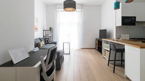 A modern kitchen with a dining area, featuring a wooden countertop, a built-in stove, and a seating area with a sofa and chairs. - Italianway Comfort - Gallura 9 B (Milan)