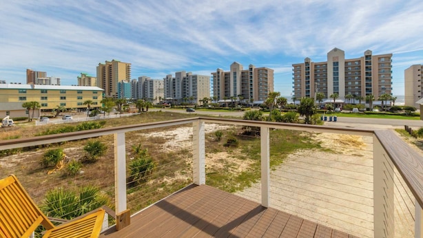 A coastal hotel with multiple high-rise buildings, a wooden deck, and a clear sky. - Sel De Vie A 4 Bedrooms Sleeps 10 (Gulf Shores)