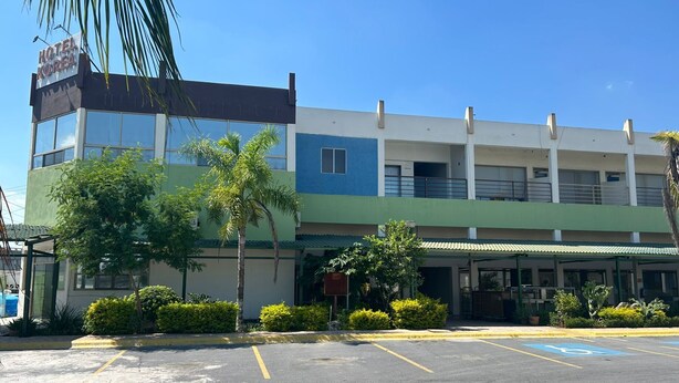 A hotel with a sign reading "HOTEL KOREA," featuring a modern facade with a green and blue color scheme, a covered parking area, and several palm trees. - HOTEL KOREA GARDEN (Apodaca)