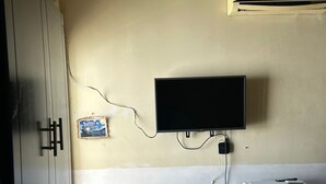 A small room with a wooden desk, a chair, a television mounted on the wall, a refrigerator, and a wardrobe. - HOTEL KOREA GARDEN (Apodaca)