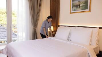 Habitación de hotel con una cama bien hecha, un cuadro en la pared y vistas al exterior a través de la ventana.